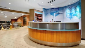 A modern reception area with a curved reception desk, seating area, and a large informational wall. - SpringHill Suites by Marriott Pittsburgh Bakery Square (Pittsburgh)
