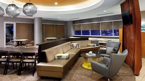A modern lounge area with a sofa, chairs, a dining table, and a TV mounted on the wall. - SpringHill Suites by Marriott Pittsburgh Bakery Square (Pittsburgh)