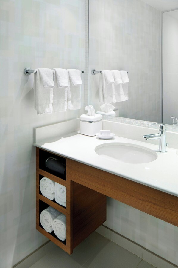 A modern bathroom with a white sink, a mirror, and two towel racks.