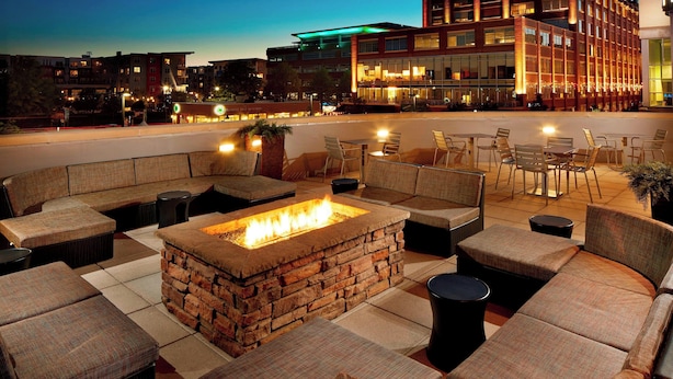 A rooftop lounge with a stone fire pit, cushioned seating, and a view of the cityscape. - SpringHill Suites by Marriott Pittsburgh Bakery Square (Pittsburgh)