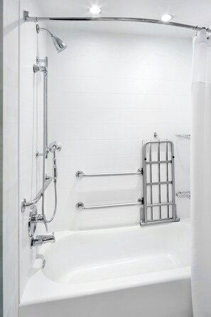 A modern bathroom with a bathtub, shower, and grab bars.