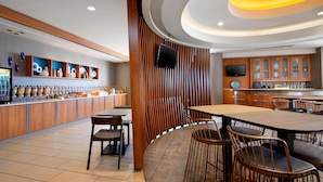 A modern restaurant interior with a bar area, seating, and a television. - SpringHill Suites by Marriott Pittsburgh Bakery Square (Pittsburgh)