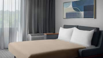 A modern hotel room with a large bed, a nightstand, and a window with curtains.