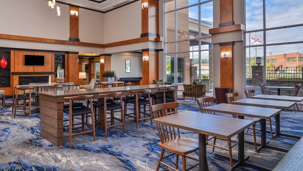 A spacious hotel lobby with a large seating area, a fireplace, and large windows offering a view of the outside. - Fairfield Inn & Suites by Marriott Pelham (Pelham)