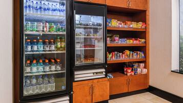 A vending machine with various beverages and snacks, and a wooden cabinet with food items.