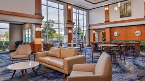 A spacious lobby with a large seating area, a bar, and large windows offering a view of the outdoors. - Fairfield Inn & Suites by Marriott Pelham (Pelham)
