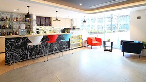 A modern bar area with a counter, stools, and a seating area with chairs. - ibis Nanjing Zhonghua (Nanjing)
