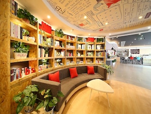 A modern library with bookshelves, a curved sofa, and a coffee table.