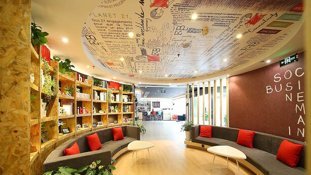 A modern interior with wooden shelving, seating areas, and a ceiling with writings. - ibis Nanjing Zhonghua (Nanjing)