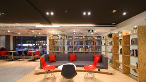 A modern library with a central seating area, wooden bookshelves, and a ceiling with a unique design. - ibis Nanjing Zhonghua (Nanjing)