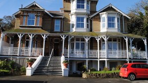 A large, two-story building with a prominent bay window and a covered porch. - The Belmont Hotel (Shanklin)