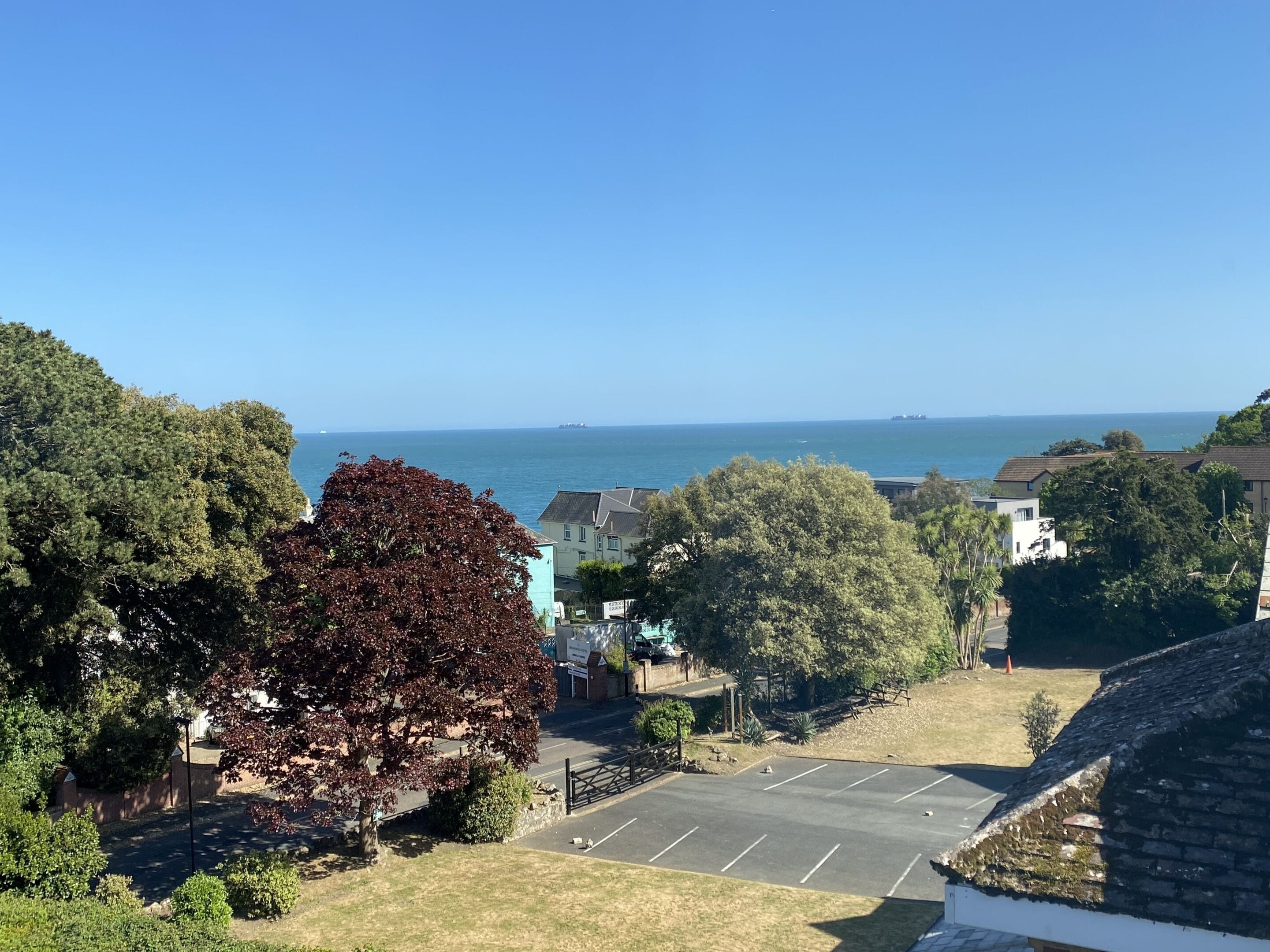 A coastal view with a parking area, buildings, and trees.