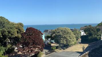 A coastal view with a parking area, buildings, and trees.