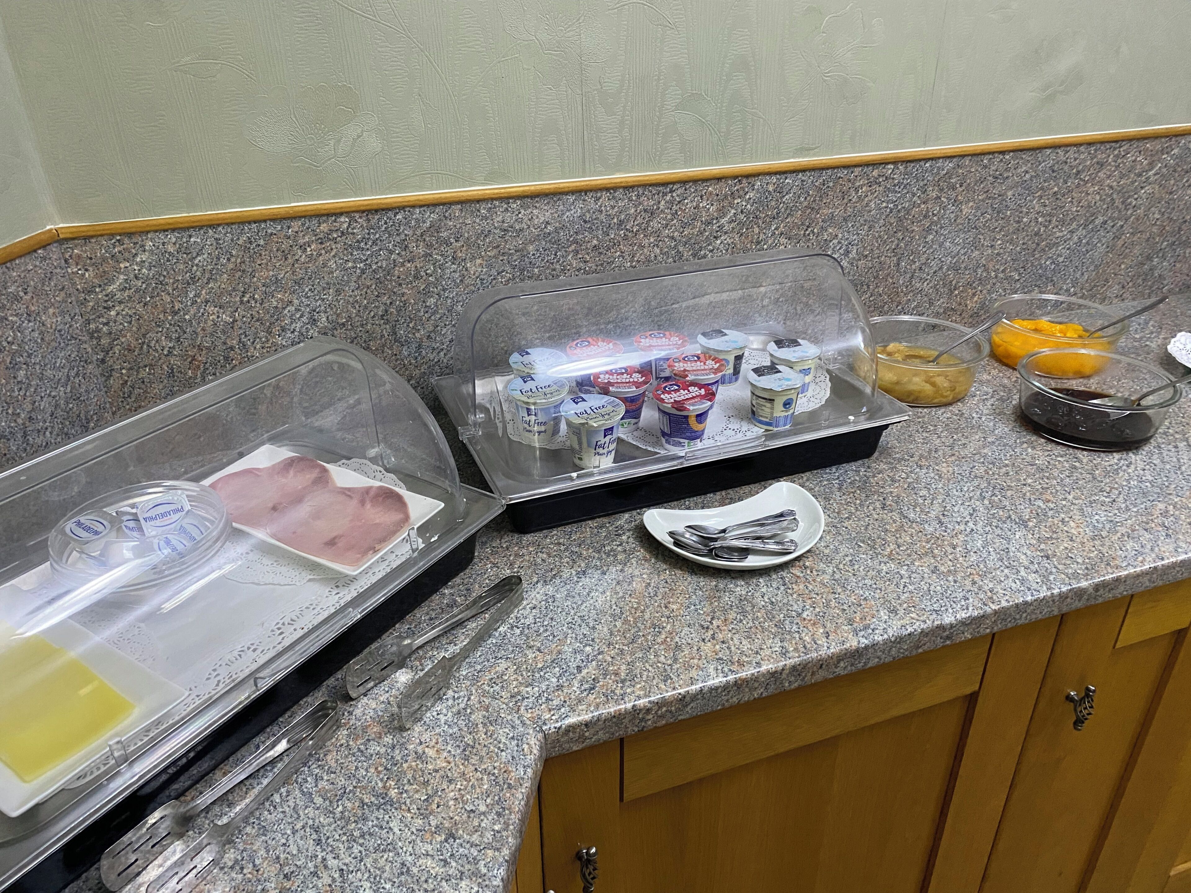 A kitchen counter with a food display case containing various dairy products and condiments.