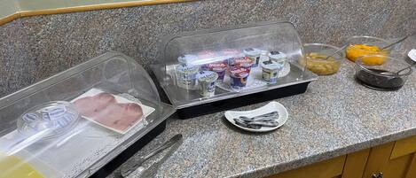 A kitchen counter with a food display case containing various dairy products and condiments.