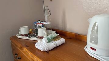 A wooden dresser with a white kettle, a glass bottle, and a tray with cups and a spoon.