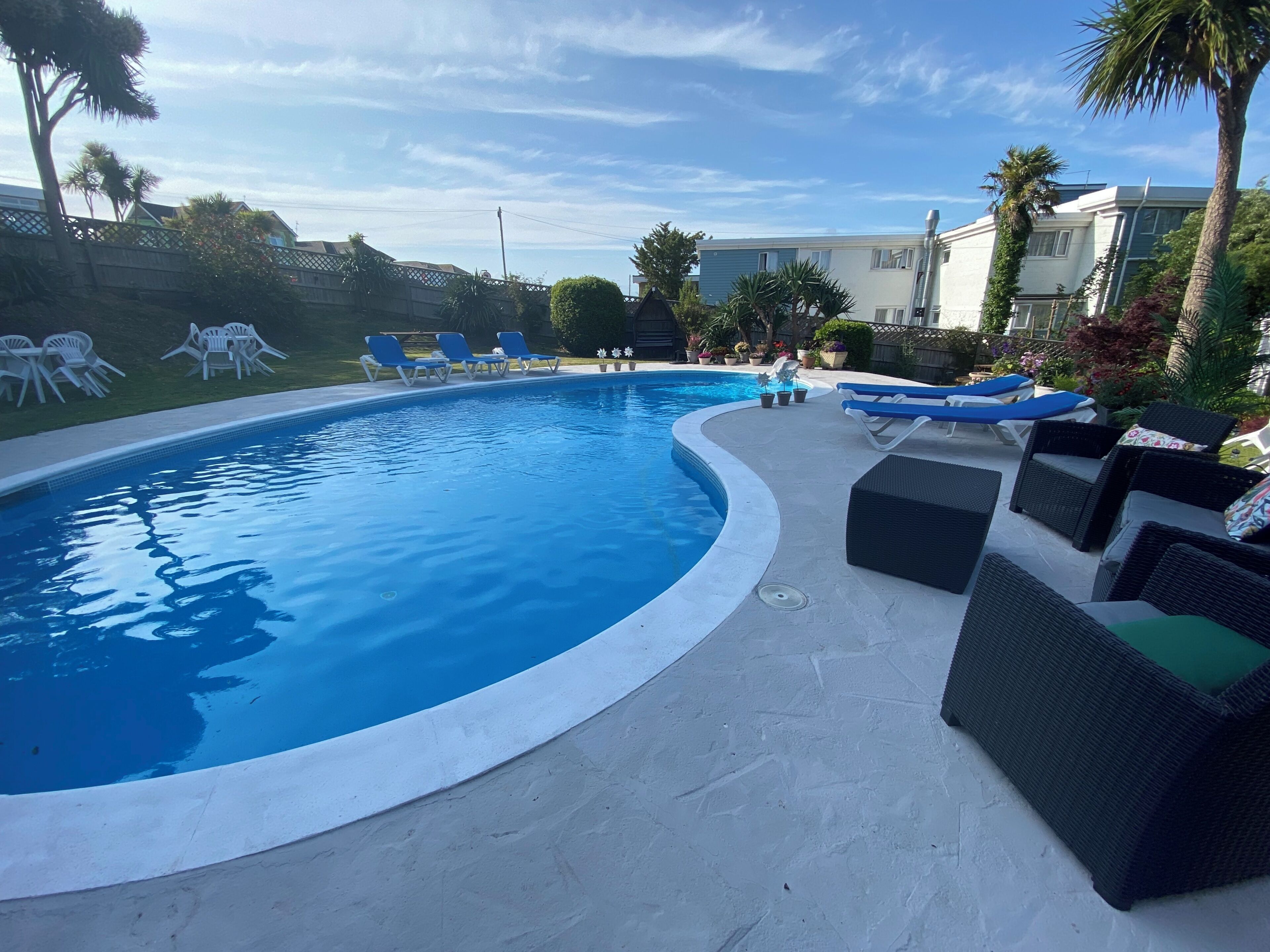 Een buitenzwembad, ligstoelen bij het zwembad