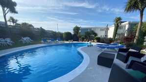 A swimming pool with lounge chairs and a patio area. - The Belmont Hotel (Shanklin)