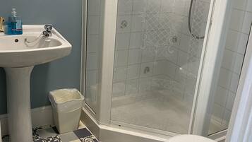 A bathroom with a pedestal sink, a toilet, and a glass-enclosed shower.