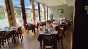 A dining area with tables set for service, large windows, and a view of the outdoors. - The Belmont Hotel (Shanklin)