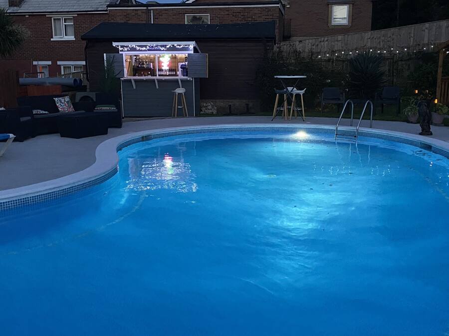En pool med ett barområde och solstolar.