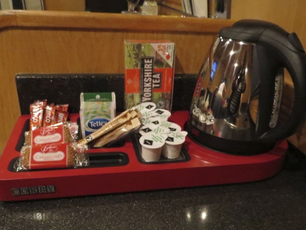 A red tray with Yorkshire Tea, Tetley tea bags, and a kettle on a countertop.