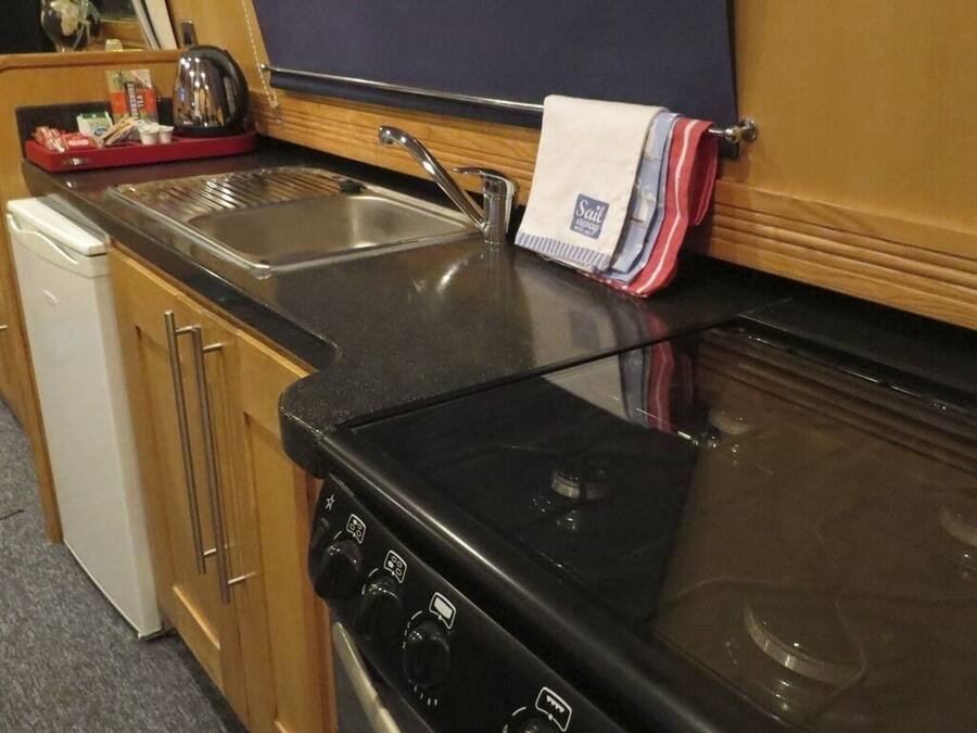 A kitchen with a stove, sink, and wooden cabinets.