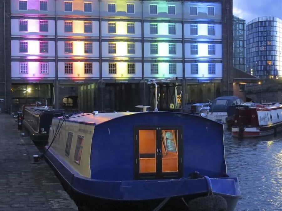 Un barco mercante atracado en un canal, con un edificio al fondo con múltiples ventanas.