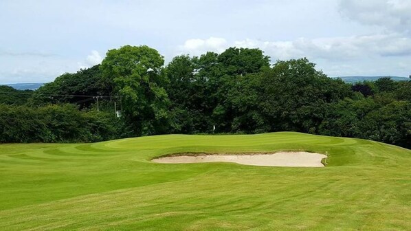A golf course with a sand bunker and lush greenery. - The Gower Golf Club (Swansea)