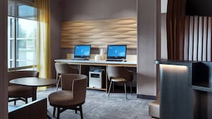 Una camera d'albergo moderna con due postazioni lavoro, una TV a schermo piatto e una scrivania reception.