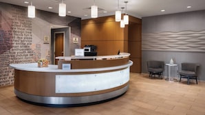 Una moderna area reception con un bancone curvo, illuminazione a sospensione e due poltrone.