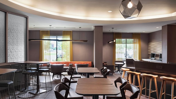 Un ristorante moderno con tavoli rotondi, sgabelli da bar e un bancone.