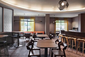 A modern restaurant with round tables, bar stools, and a counter.