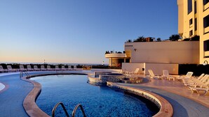 A swimming pool with a circular design, surrounded by lounge chairs and a building with a flat roof. - Park Hotel Mirabeau (Gasperina)