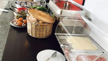 Disposición de un bufé con distintos alimentos, como pan, huevos y carne, sobre una mesa.