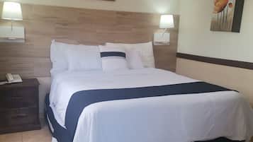 Habitación de hotel con una cama grande, dos mesitas de noche con lámparas, un cabecero de madera y un cuadro en la pared.