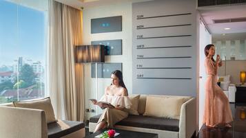 A modern hotel room with a large window, a sofa, a coffee table with a vase, and a wall calendar.