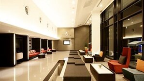 A modern hotel lobby with a long reception desk, comfortable seating areas, and large windows. - Tsix5 Hotel (Pattaya)