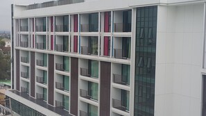 Un immeuble à plusieurs étages doté d’une architecture moderne, avec des balcons pourvus de rampes en métal et de grandes fenêtres.