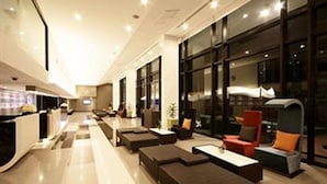 A modern lobby with a long reception desk, comfortable seating areas, and large windows. - Tsix5 Hotel (Pattaya)