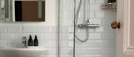 A bathroom with a white sink, mirror, shower, and patterned floor tiles.