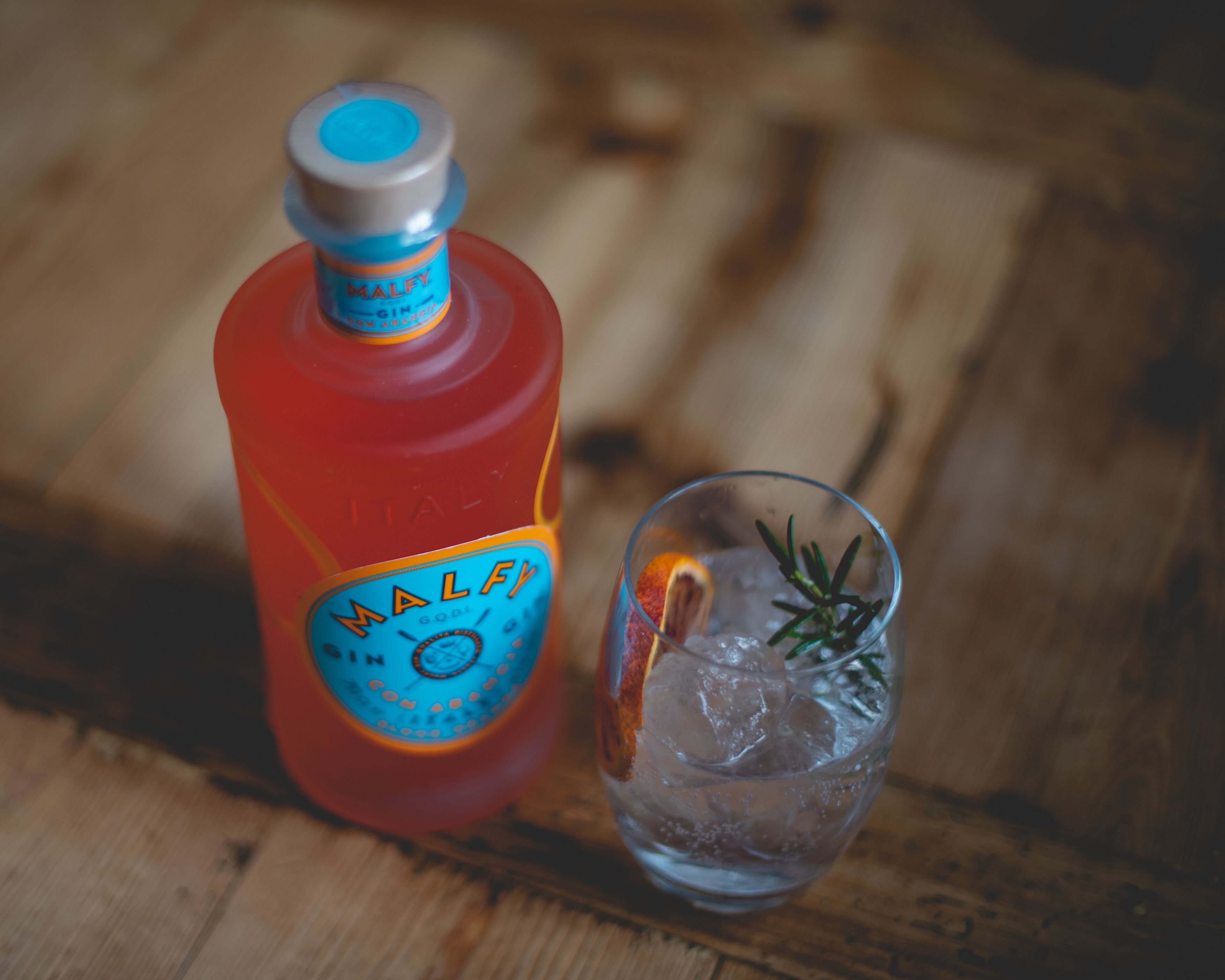 A bottle of Malfy gin and a glass with ice and a slice of orange.