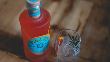 Une bouteille de gin Malfy, un verre rempli de glaçons et une tranche d’orange.