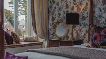 A bedroom with a window seat, a mirror, and a bedside table.