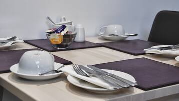 A neatly arranged dining table with plates, cutlery, and a bowl of cereal.