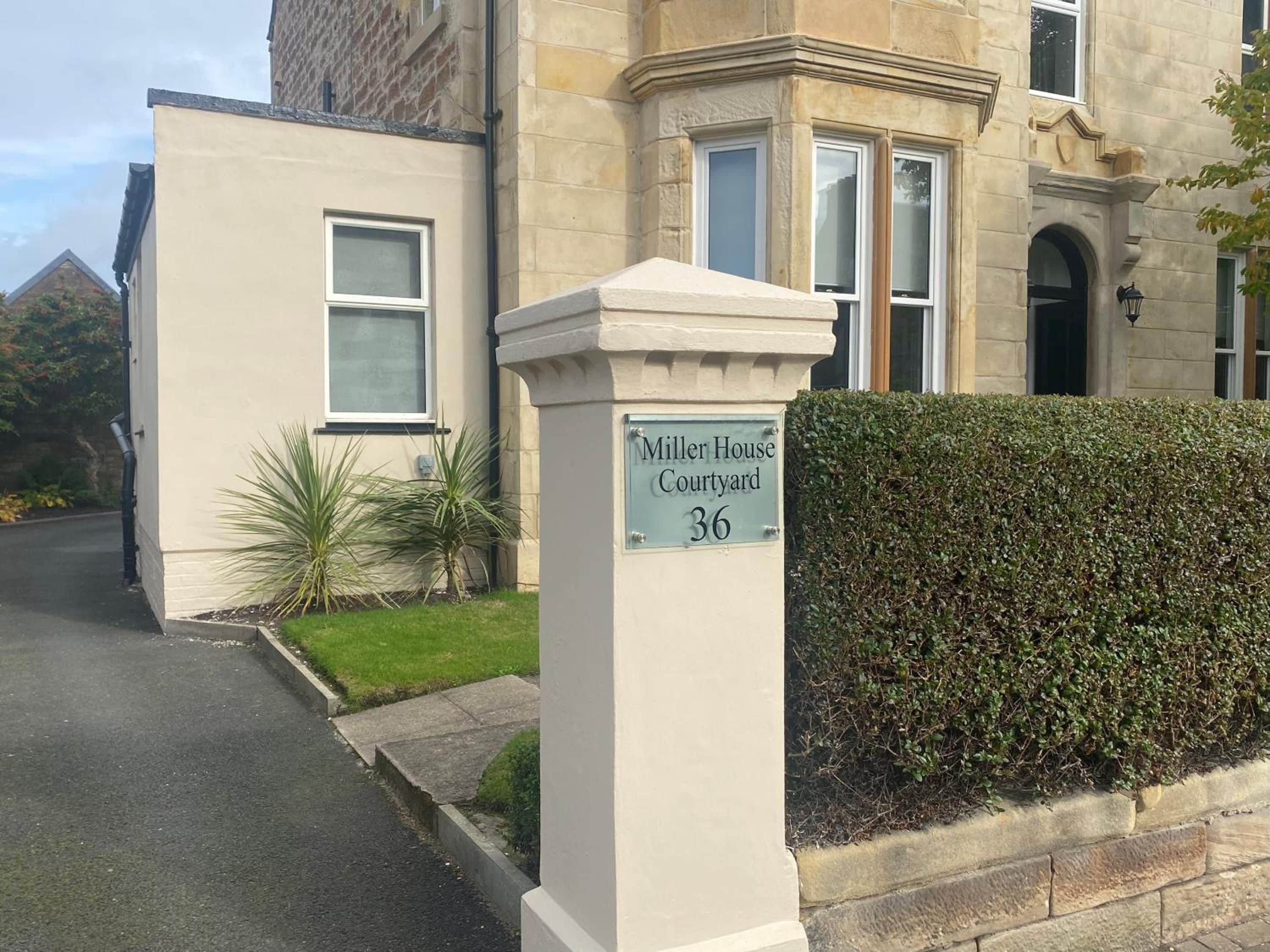 A building with a sign reading 'Miller House Courtyard 36' indicating a property number.