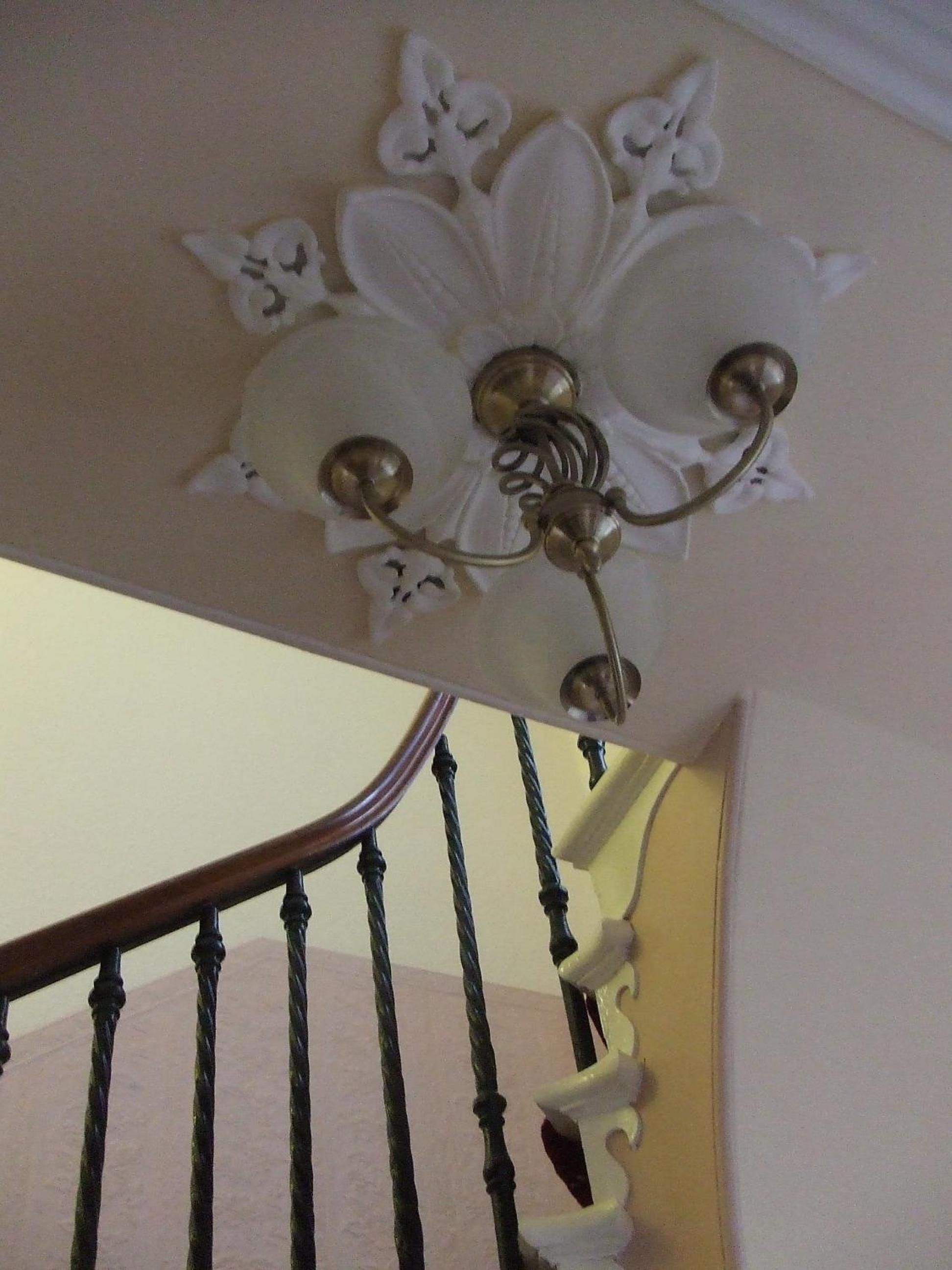 A staircase with a decorative ceiling fixture and a wooden handrail.