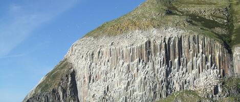 Une falaise côtière avec des formations rocheuses verticales et un ciel dégagé.