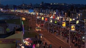Eine belebte Straßenszene bei Nacht, beleuchtete Schilder und eine Menschenmenge.