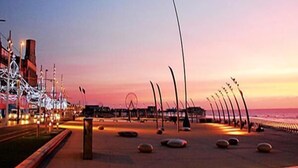 Eine Uferpromenade mit gewundener Wege, Laternen und einem fernen Riesenrad.